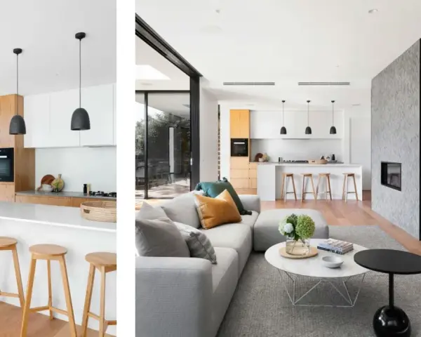 Cocina tipo americana moderna con isla, taburetes de madera y sala de estar contigua con chimenea de piedra.