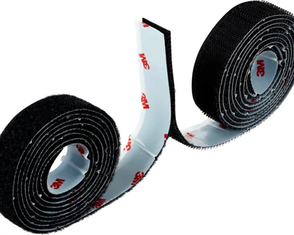 Dos rollos de cinta adhesiva negra, que es velcro, con el logo de 3M en el reverso.