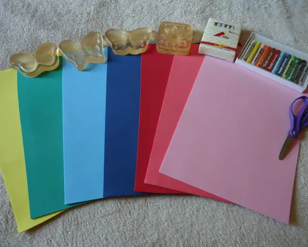 Hojas de goma eva de varios colores, pasteles, tijeras y sellos de mariposa. ¡Ideal para manualidades!