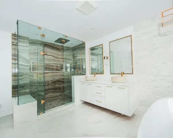 Elegante baño moderno con ducha de cristal, lavabos sobre encimera y detalles dorados. Ideas para decorar un baño de lujo.