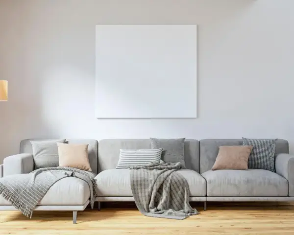 Sofá gris con cojines en tonos tierra y grises, mantas y planta verde. Ideas para combinar cojines con sofá gris.