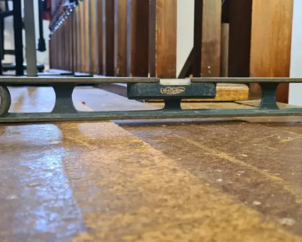 Nivelando un suelo de madera antiguo con un nivel de burbuja. La herramienta muestra que el suelo está ligeramente inclinado.