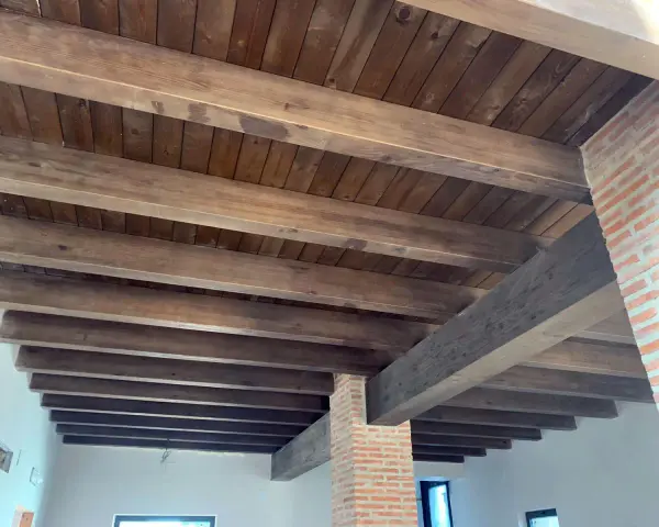 Tejado de madera a un agua con vigas rústicas y entablado oscuro. Ideal para un estilo campestre.