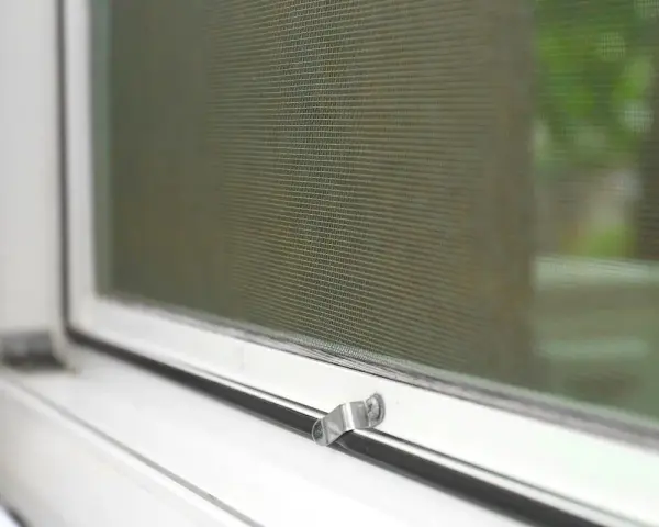 Detalle de mosquitera en ventana blanca. Aprende cómo limpiar mosquiteras para un hogar impecable.