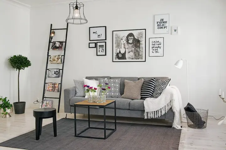 Ideas para combinar cuadros en la pared: un salón moderno con sofá gris, escalera decorativa y arte gráfico.
