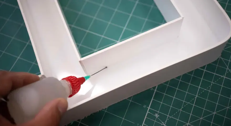 Aplicando adhesivo con precisión para saber como pegar el metacrilato y unir las piezas de forma segura.