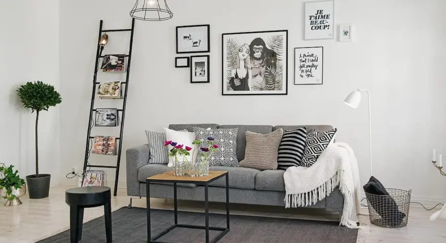Ideas para combinar cuadros en la pared: un salón moderno con sofá gris, escalera decorativa y arte gráfico.
