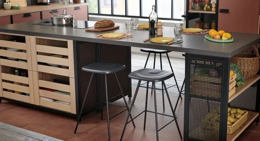 Cocina moderna con isla central y taburetes de altura taburete barra 90. Frutas, pan y vajilla sobre la encimera.