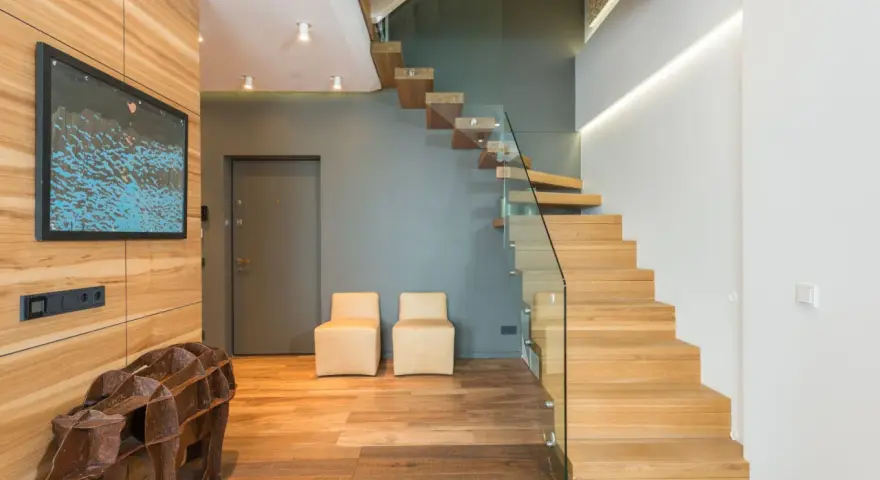 Moderna entrada con una impresionante escalera de madera flotante.