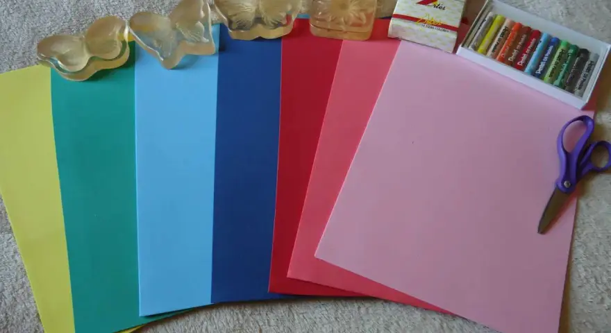 Hojas de goma eva de varios colores, pasteles, tijeras y sellos de mariposa. ¡Ideal para manualidades!