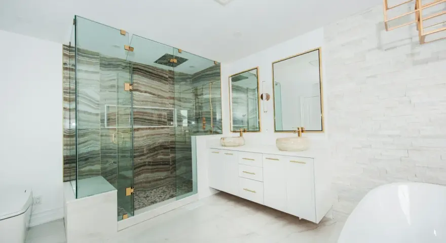 Elegante baño moderno con ducha de cristal, lavabos sobre encimera y detalles dorados. Ideas para decorar un baño de lujo.