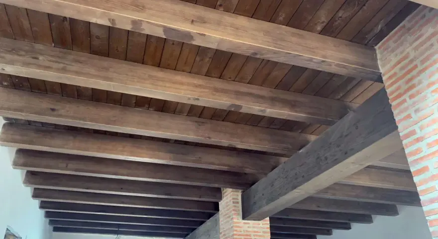 Tejado de madera a un agua con vigas rústicas y entablado oscuro. Ideal para un estilo campestre.