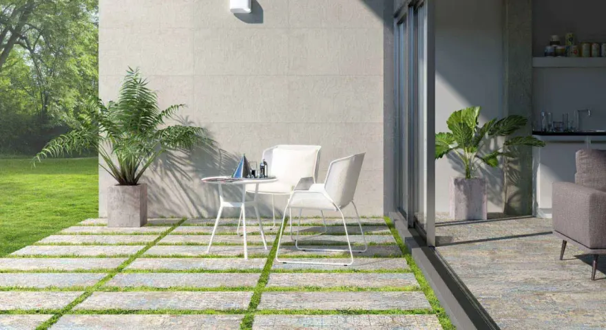 Terrazas pequeñas con encanto: un camino de baldosas y césped lleva a una mesa y sillas blancas, con plantas y un jardín verde.