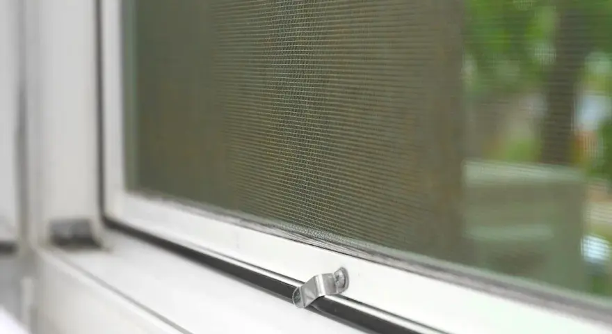Detalle de mosquitera en ventana blanca. Aprende cómo limpiar mosquiteras para un hogar impecable.
