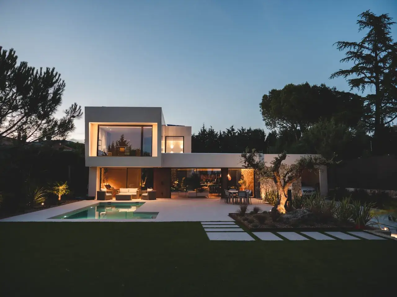 Moderna casa con piscina y jard&iacute;n iluminado. &iquest;Cu&aacute;nto dura una casa prefabricada? Esta casa de dise&ntilde;o moderno, con l&iacute;neas limpias y grandes ventanales, parece hecha para durar.