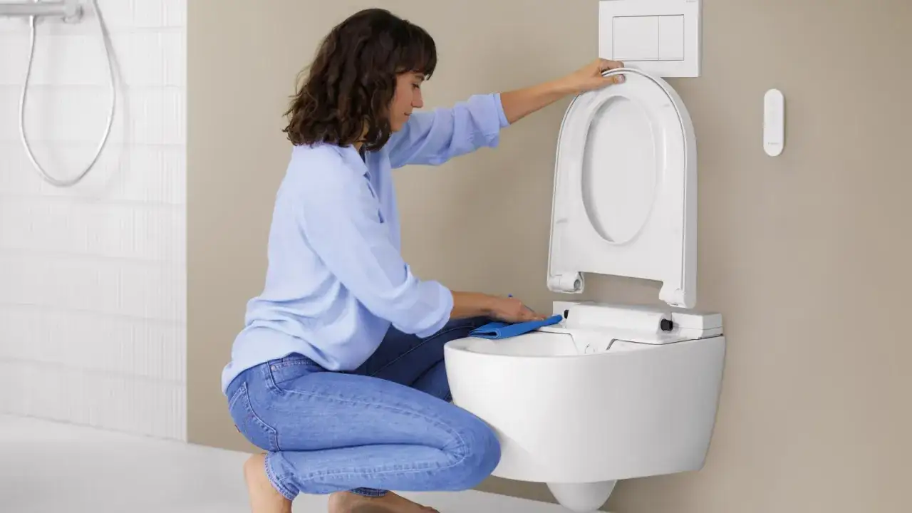 Mujer limpiando el fondo del inodoro con un pa&ntilde;o azul.