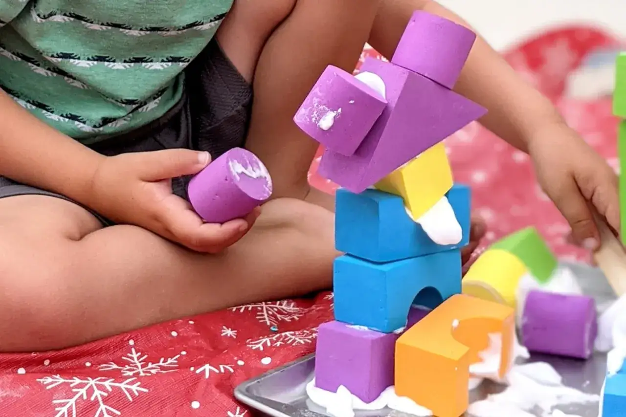 Un niño juega con bloques de goma eva de colores. La goma eva se puede mojar, perfecta para actividades divertidas y creativas.