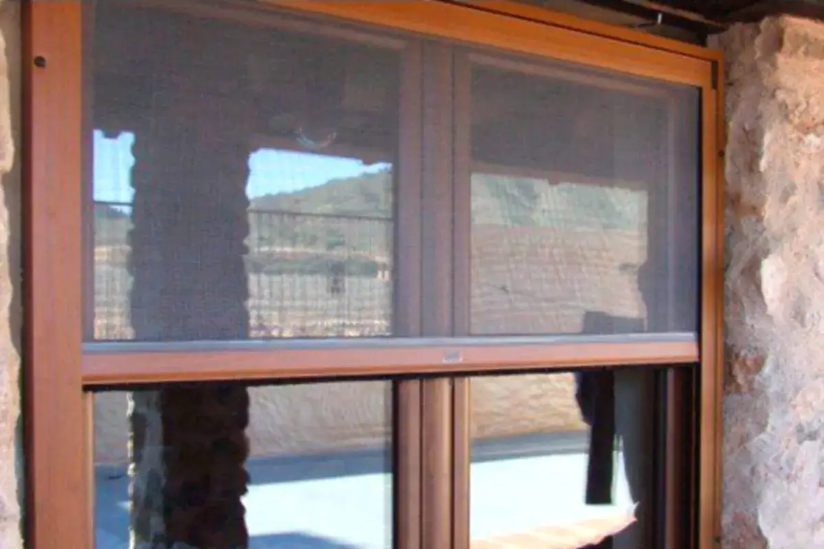 Ventana con mosquitera enrollable instalada, ideal para proteger tu hogar de insectos y disfrutar del exterior.