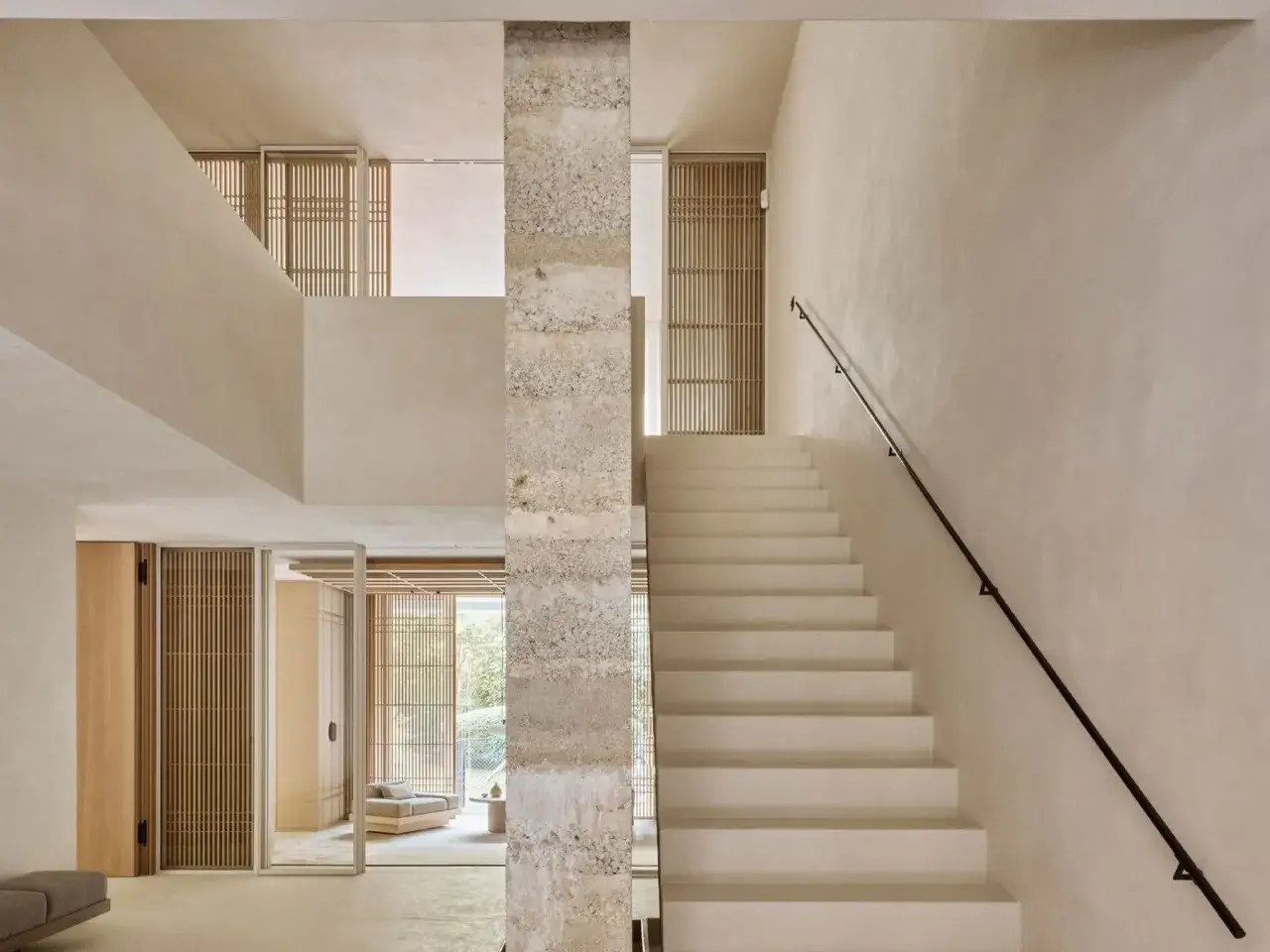 Elegante escalera de hormig&oacute;n con barandilla negra. La pared de la escalera es ideal para decorar, con puertas de madera y celos&iacute;as que aportan calidez.