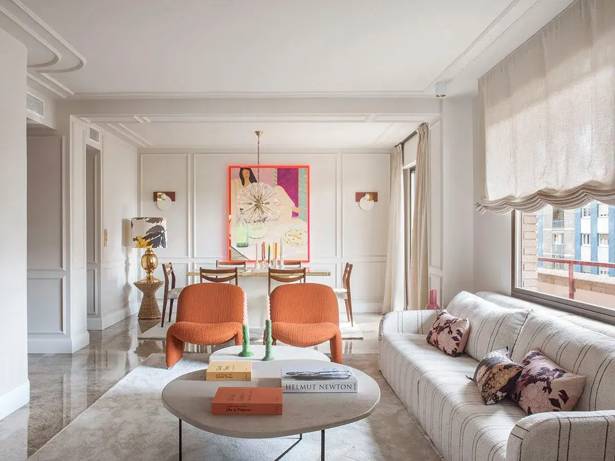 Salones modernos y elegantes con sof&aacute; a rayas, sillones naranjas y un cuadro vibrante.