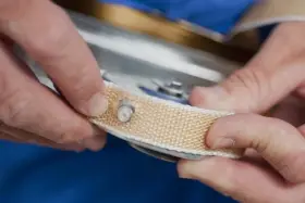 Manos sujetando una cinta de persiana rota, preparándose para cambiarla.