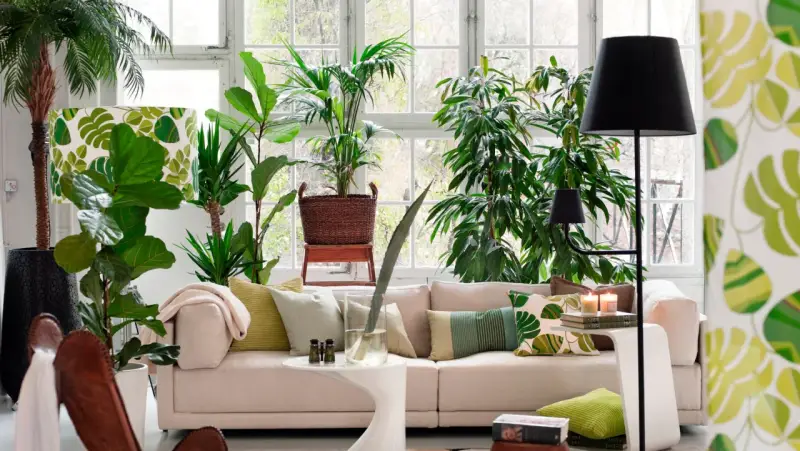 Un salón moderno y luminoso, ideal para decorar con plantas. Un sofá beige, cojines verdes y muchas plantas crean un oasis de frescura.